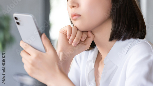 スマートフォンを持って考えごとをする女性