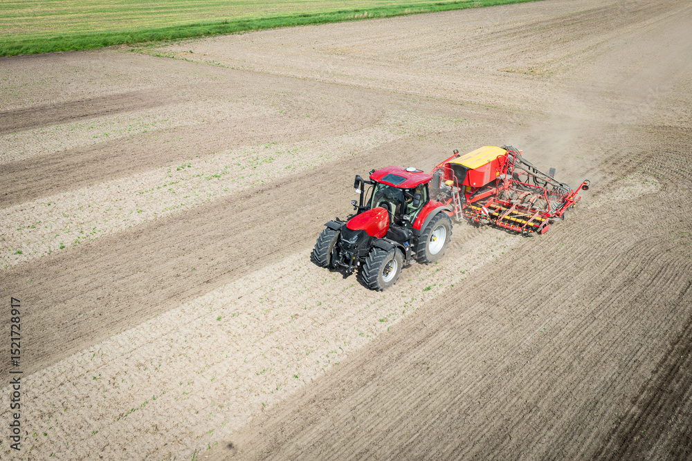 Fototapeta premium Traktor mit moderner Direkt - Sämaschine beim Drillen auf einem staubigen Feld, Luftbild.