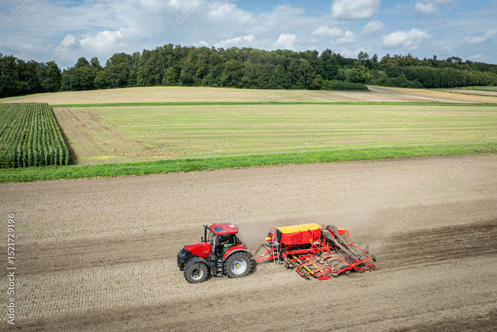 Fototapeta premium Traktor mit moderner Direkt - Sämaschine beim Drillen auf einem staubigen Feld, Luftbild.