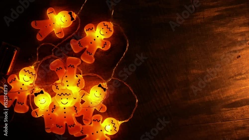 Christmas Glowing Gingerbread man garland on wood background.Warm light Christmas garland. Cozy winter holidays atmosphere. 4k footage