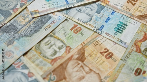 Peruvian currency notes of various denominations spread out in a close-up view, depicting different historical figures and vibrant designs.