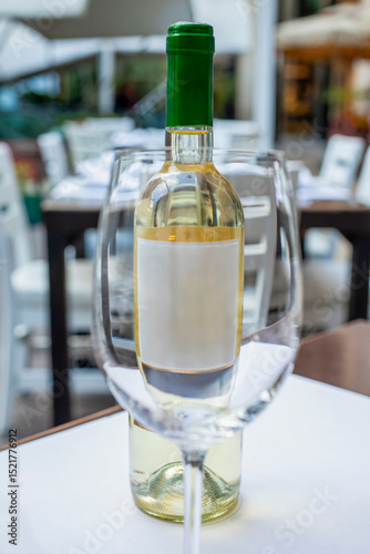 Bottle of white wine with blank label in elegant restaurant outdoor setting