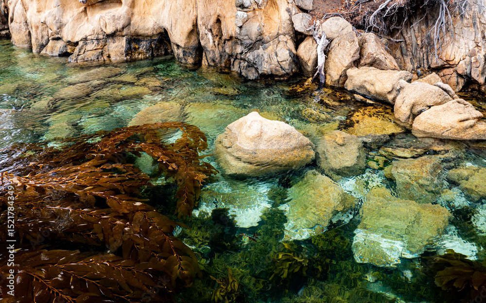 Fototapeta premium Cliff with rocks under water clear visible blue ocean shore rocky inaccessible