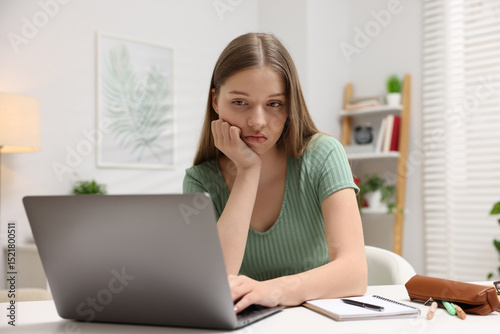 Free Download Frustrated teenage girl doing homework with laptop at white desk indoors - GFXLoad