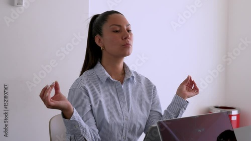 Hispanic office worker practicing mindfulness meditation at her desk