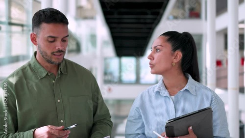 Two business professionals, a man and a woman, are having a discussion in a modern office building