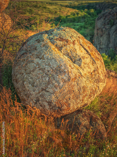 portrait view to huge round granite boulder in golden light of sun