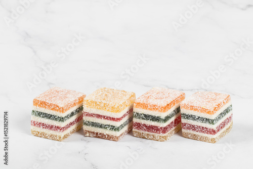 Layered multicolored jelly marmalade in the shape of a cube. White background. Copy space