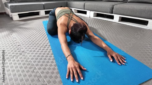 Practicing a deep stretching yoga child pose on a mat in a calm indoor area. The individual focuses on relaxation and flexibility, surrounded by a soothing environment in the afternoon.