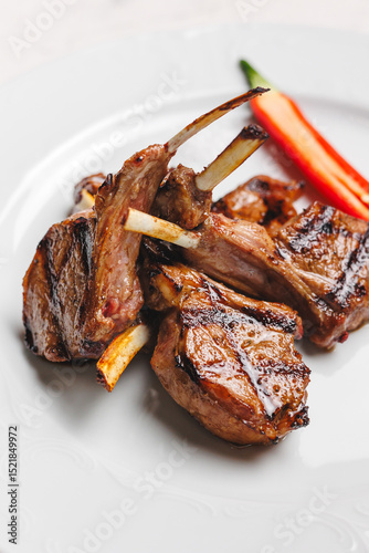 Grilled lamb chops with red chili on a white plate
