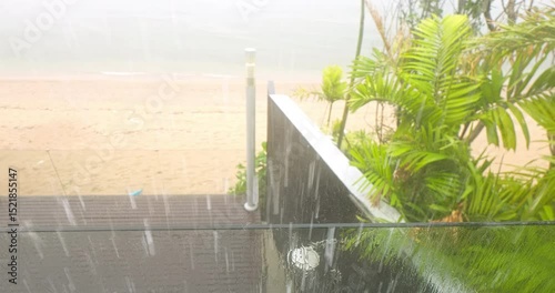 view from balcony from luxury villa to palm trees on the beach in heavy rain, nobody