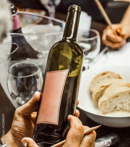 Sommelier examining wine bottle with blank label during tasting