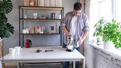 young millennial man grinding coffee at home , making coffee in the morning