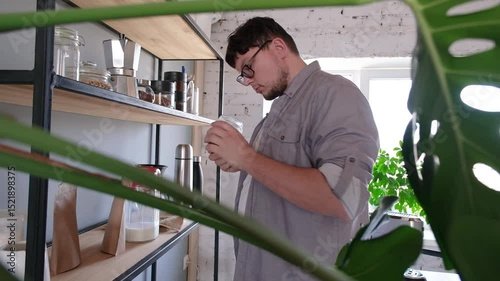 young millennial man grinding coffee at home , making coffee in the morning