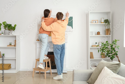 Young couple hanging painti...