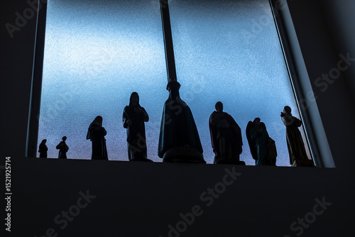 Fotografie Silhouettes of statues of Catholic saints on a windowsill, including Our Lady of Aparecida, Saint George and others — symbols of Brazil's religious traditions and popular devotions