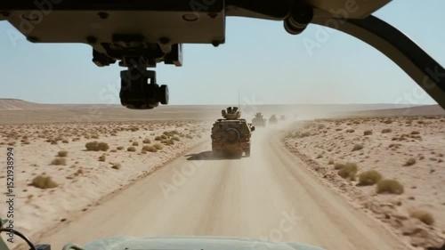 Military convoy driving through arid desert landscape on a dusty road expedition