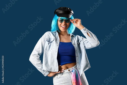 Stylish young African-American woman in wig on blue background