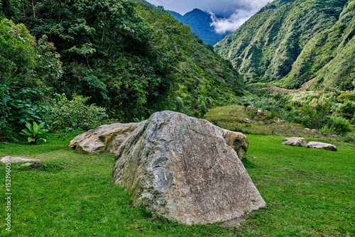 Large boulders resting on lush green grass in a serene park, surrounded by vibrant foliage and majestic mountains, creating a peaceful outdoor atmosphere for nature lovers in Ecuador.Latin America