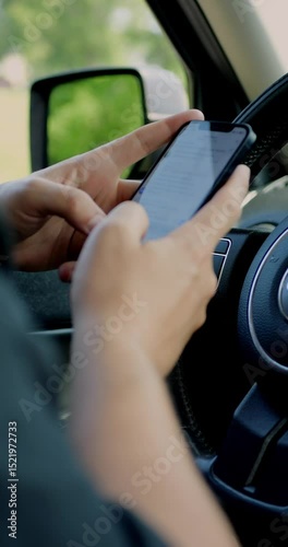 Man using a mobile phone to check email for work or text SMS. Driver reads news on mobile phone inside car. Screen is blurred. Focus on finger hand. Vertical shot.