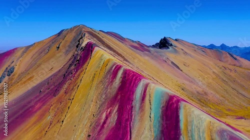 Colorful rainbow spans across the Andean mountains in Peru, with rugged terrain and moody clouds creating a dramatic natural scene.