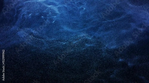Abstract motion background features swirling blue particles creating a wave-like or smoke-like effect. Seamless loop of digital render depicting energy, data, or magical flow. 3D render