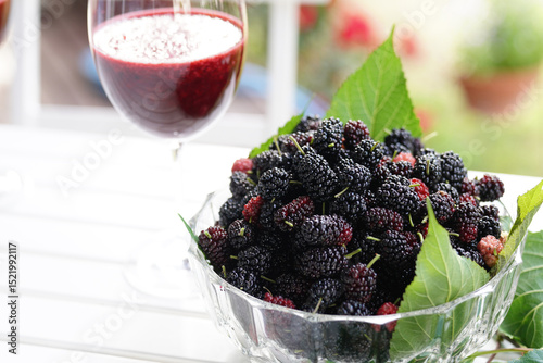 Mulberries in glass bowl with glasses of mulberry juice.