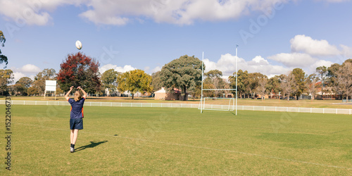 Teenage boy practicing ball handling skills on empty rugby field