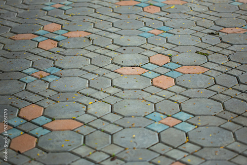 Close up shot of paving stone concrete block in octagon, hexagon and square shape, in vintage grey and brown color , also with tiny fallen leaves on their surface