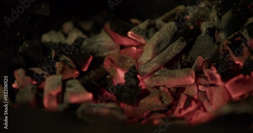 Static close-up of the blacksmith’s forge. The blacksmith uses a poking stick to stir the glowing coals.
