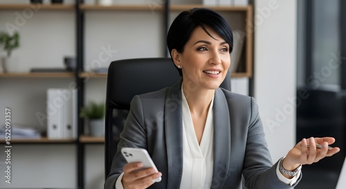 Business woman with phone in office: professional portrait of executive female in gray suit and white blouse