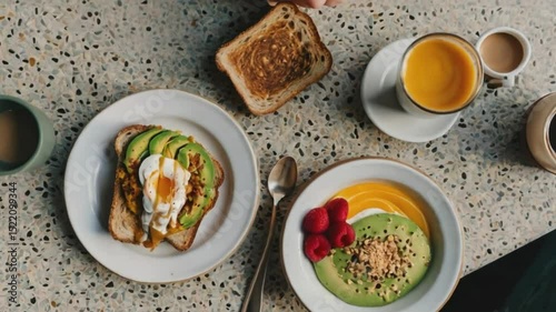 Aesthetic flat lay of a brunch table with avocado toast, smoothie bowl, and coffee, on a terrazzo table with hands reaching in, styled in bright, natural light.