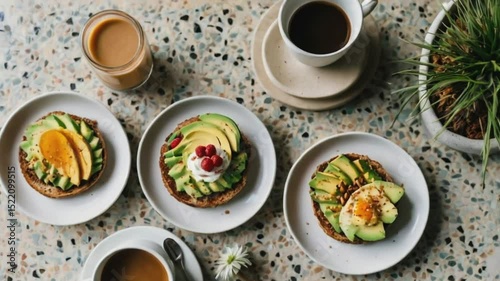 Aesthetic flat lay of a brunch table with avocado toast, smoothie bowl, and coffee, on a terrazzo table with hands reaching in, styled in bright, natural light.