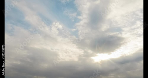 Beautiful fluffy cumulus clouds in a bright blue sky on a clear summer day. Sun rays shine through, creating a dramatic, peaceful atmosphere. Perfect for nature, weather, backgrounds, and scenic sky