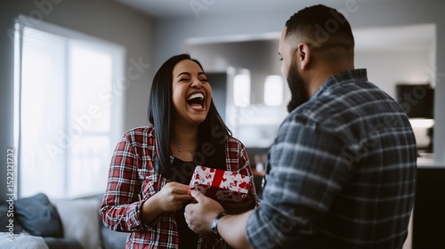 Woman laughing receiving a gift from a man in a plaid shirt in a living room with natural light source
