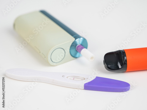 Pregnancy test and electronic cigarette on white table. 