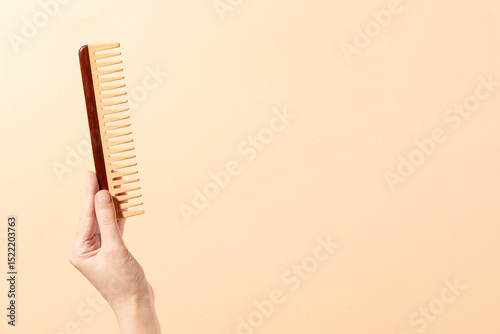 Hand holding Wooden Comb on white background with shadow simple image photo for beauty tools and market place