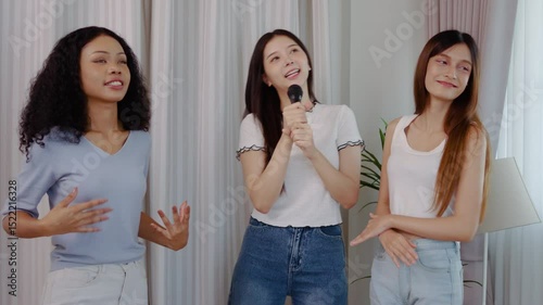 Cheerful three young asian and mixed race woman celebrate friendship as they sing and dance together with infectious enthusiasm, sharing laughter and joy, Dancer shows body wave and other movements