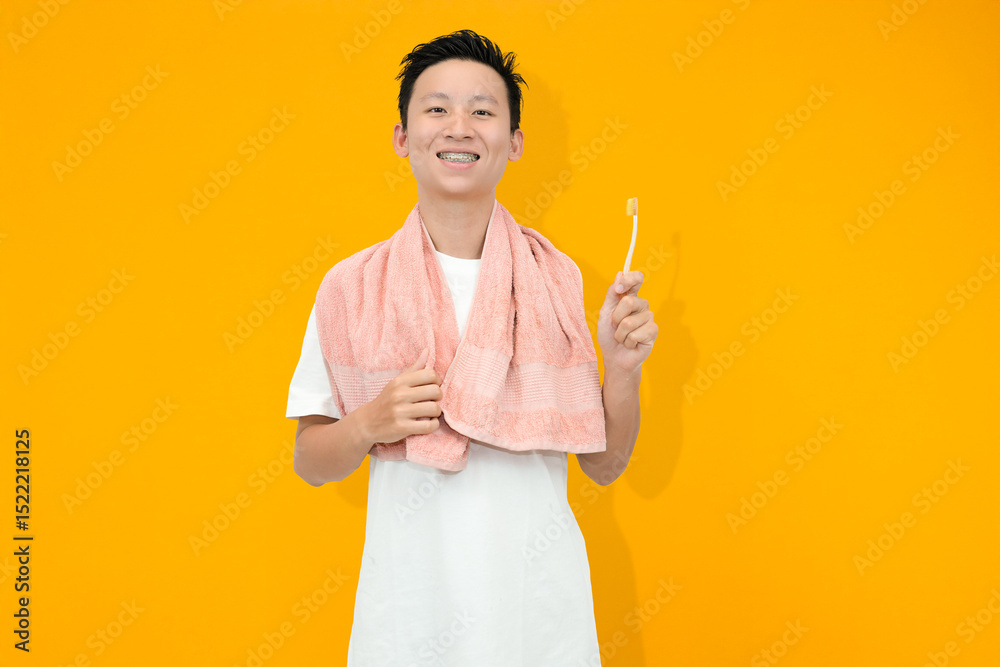 smiling young asian man holding toothbrush in studio orange background smiling young asian man holding toothbrush in studio orange background