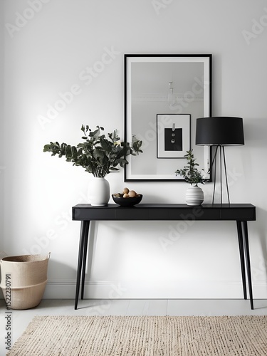 A modern entryway with a minimalist black console table, a framed picture on the wall and various decorative items such as a vase with branches, candlesticks and bowls. 
