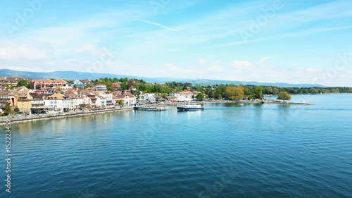 Aerial: boat on Lake Geneva arriving at the wharf during the day in Nyon, canton of Vaud, Switzerland, orbit drone shot