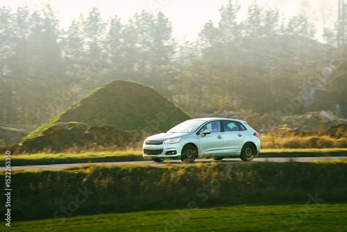 Modern hatchback driving on a road near trees drive on a sunny day