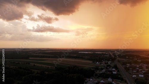 Orange sky with storm clouds over rural landscape at sunset