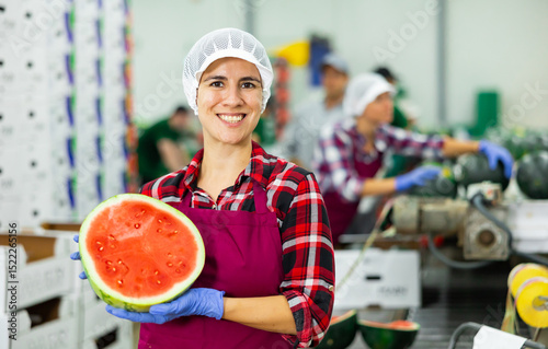 Wallpaper Mural Happy Hispanic woman fruit processing factory worker holding half of ripe red watermelon while standing in workshop near sorting line Torontodigital.ca