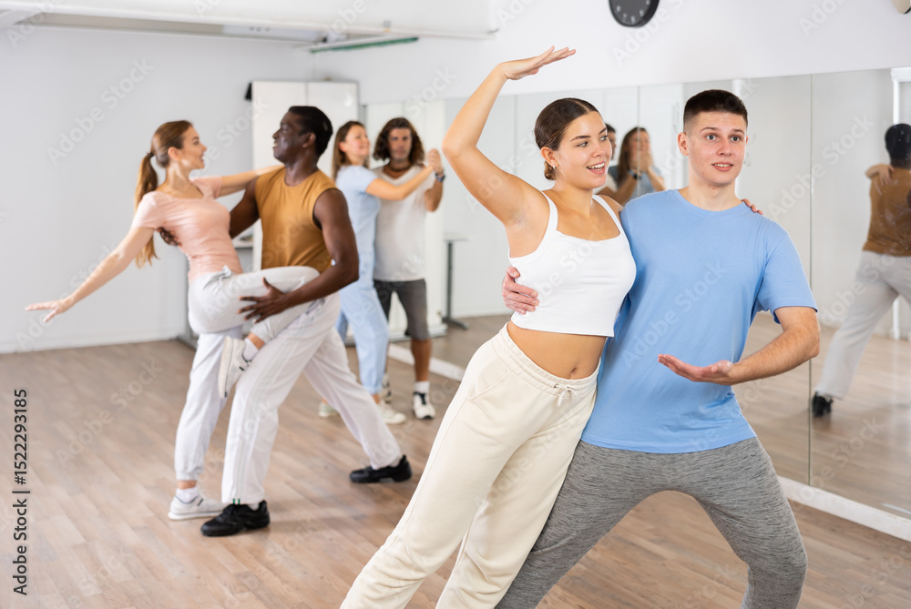 Fototapeta premium Joyful young adult couples learning passionate pair dancing during practicing in choreography class
