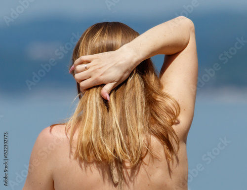 A woman with long brown hair is standing on a beach