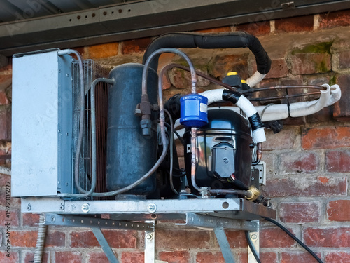 The refrigerator compressor is mounted on the wall of the building.