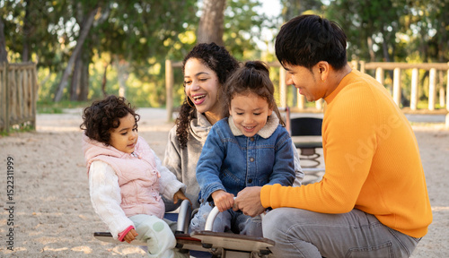 Smiling latin parents enjoying playtime with daughters on seesaw in park