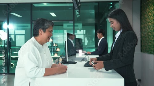Senior Passenger at Airport Check-In, Asian Woman Verifying Passport with Friendly Airline Staff for International Travel at Departure Counter