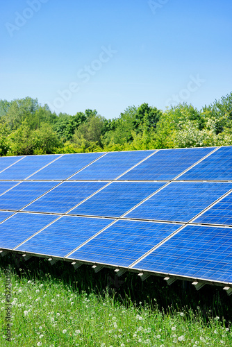 A modern solar plant in a green landscape and trees in the background show the progress of sustainable energy production and the transition to ecologically renewable energy - Munich, Germany